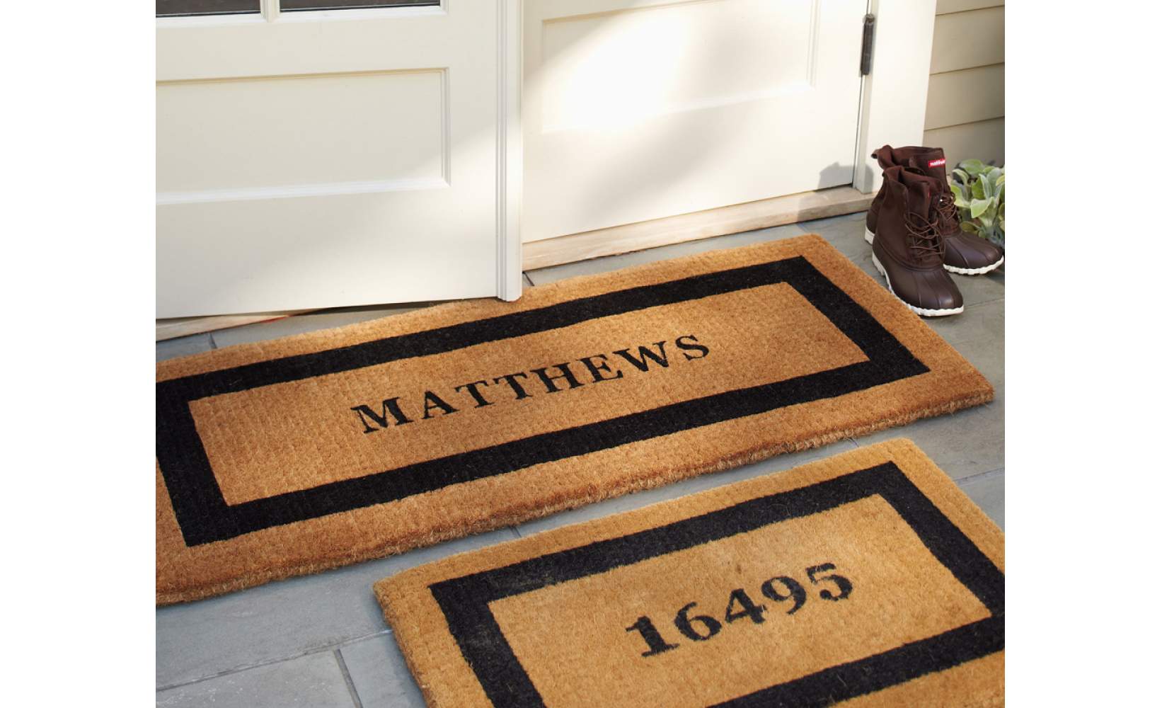 Set of personalized doormats outside a white front door.