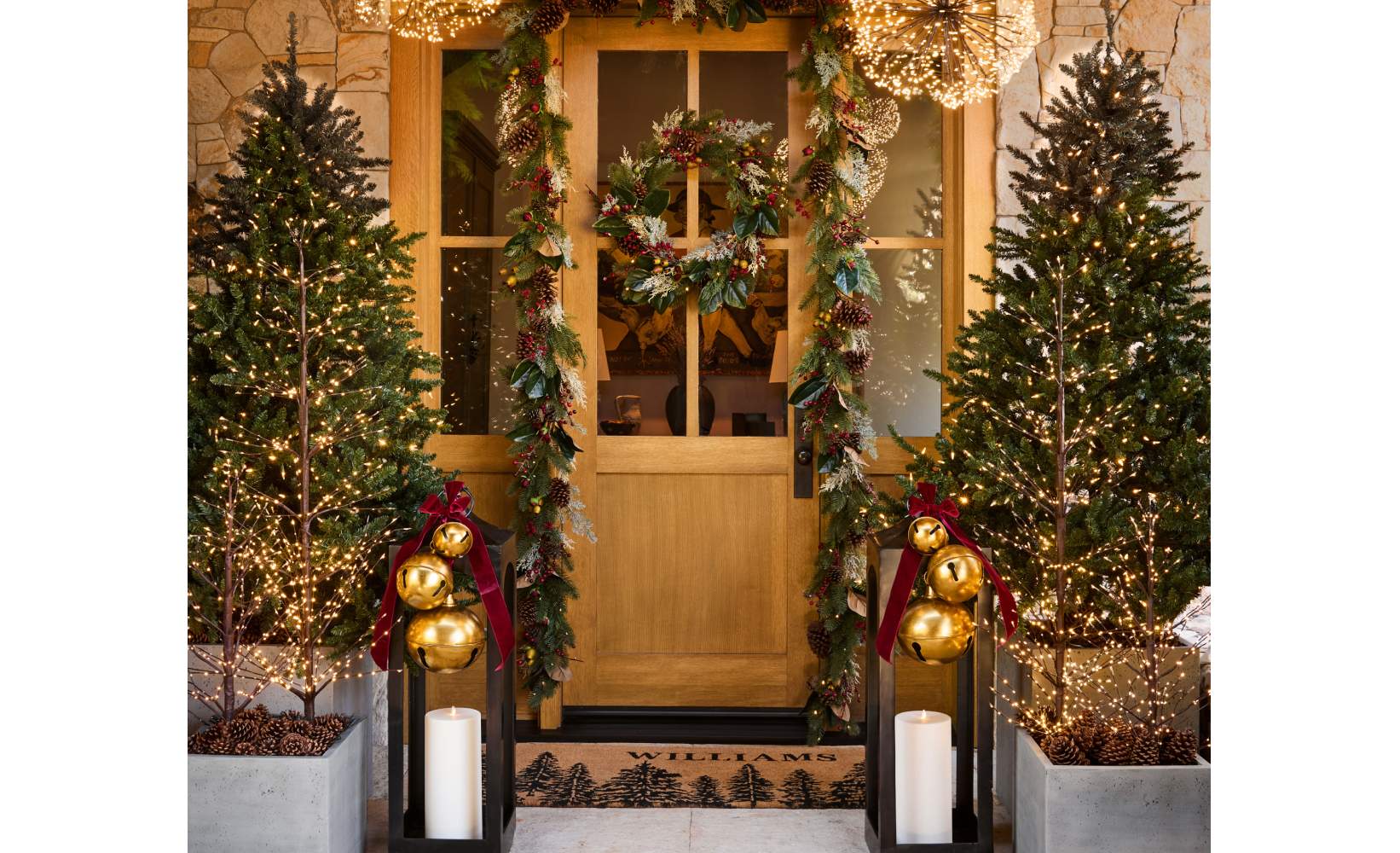 Festive front porch decorated for the holidays, featuring a wooden door framed by a garland of greenery, pinecones, and red berries.