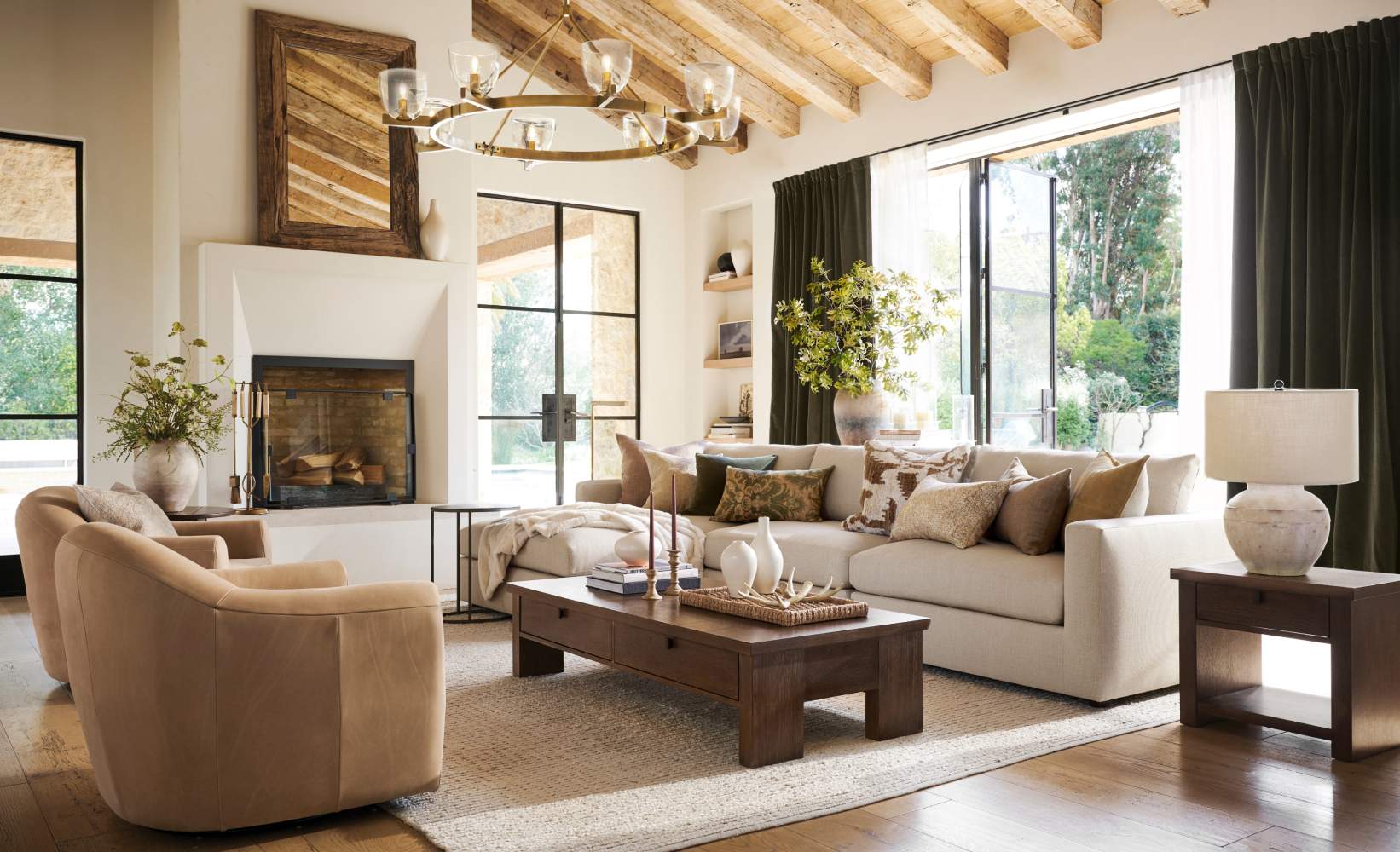 Spacious living room with a rustic-modern design featuring a large beige sectional sofa with throw pillows, a wooden coffee table, and light tan armchairs.