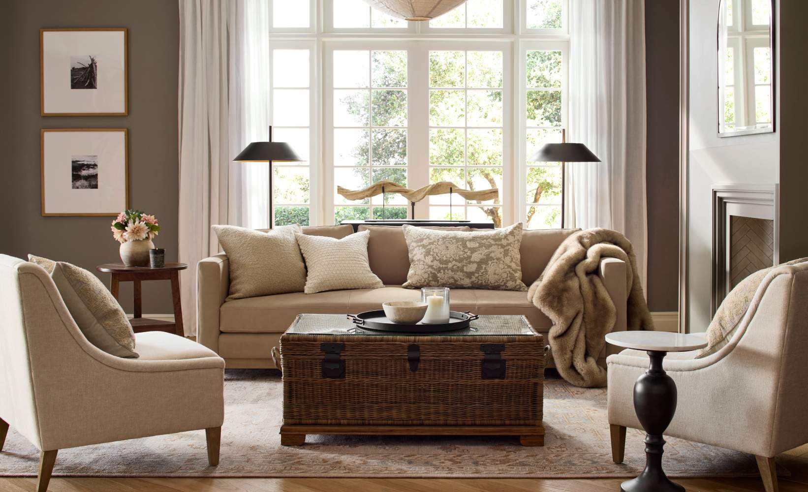 Traditional living room with a beige sofa, accent chairs, wicker trunk coffee table, and large windows bringing in natural light. Traditional living room with a beige sofa, accent chairs, wicker trunk coffee table, and large windows bringing in natural light.