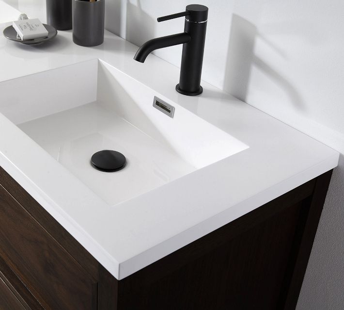 Close-up of single sink area with white countertop and black faucet.