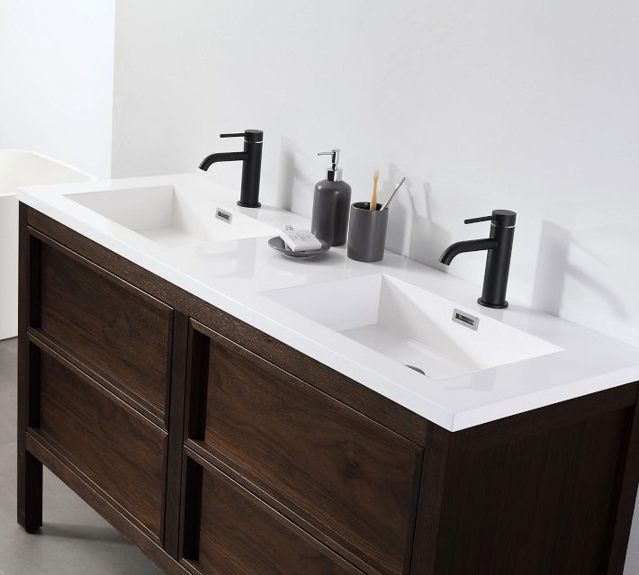 Close-up of double sink vanity with white countertop, black faucets, and bathroom accessories.