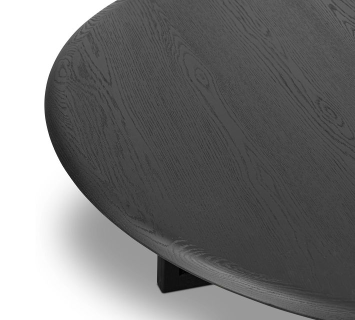 Close-up corner of dark wood round table showing edge and leg