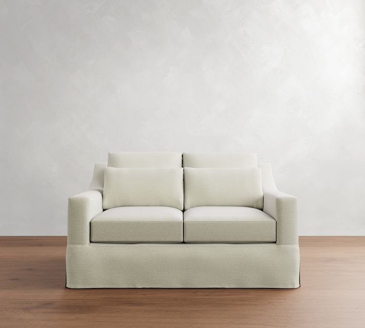Two-seater cream sofa against textured gray wall.