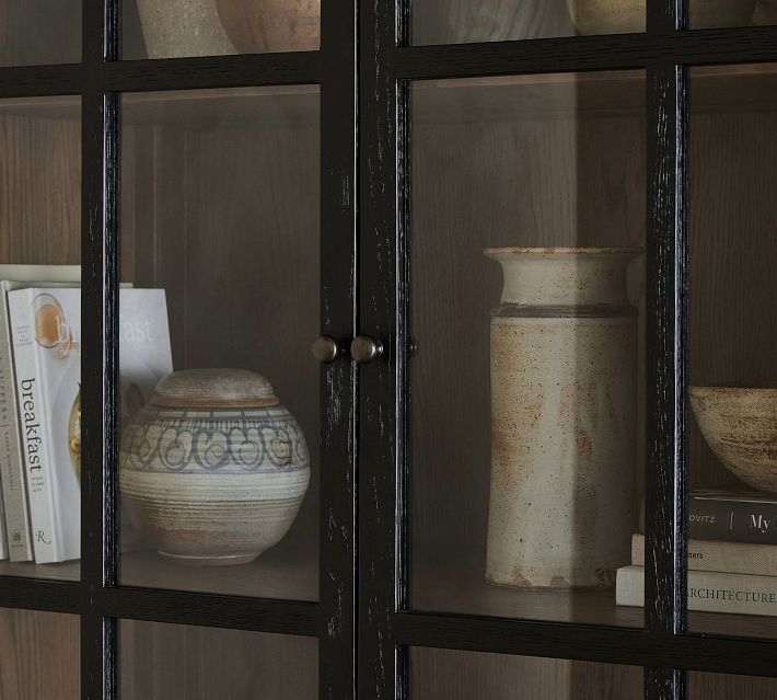 Close-up of glass cabinet doors with pottery visible inside, showing closet hardware.