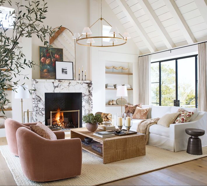 Open living room with white sofas, gold chandelier, and large windows.