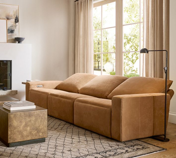 Close-up of armrest and seat cushion of tan leather sofa, showing stitching and leather grain.