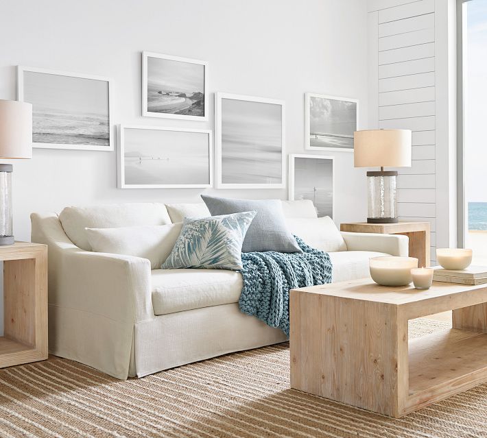 Living room with white sofa, gray and blue pillows, modern wooden coffee tables.