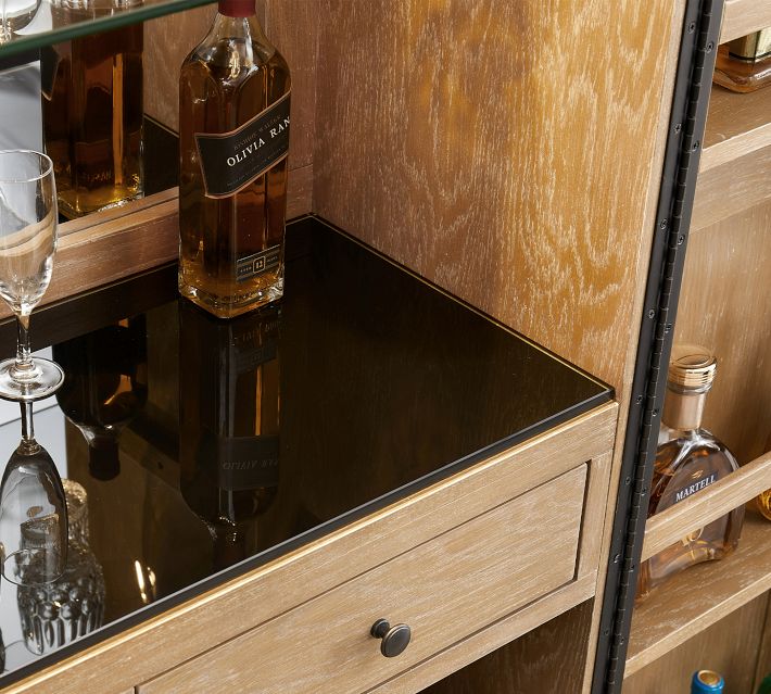 Glass shelf with a bottle of whiskey and drinkware inside a cabinet.
