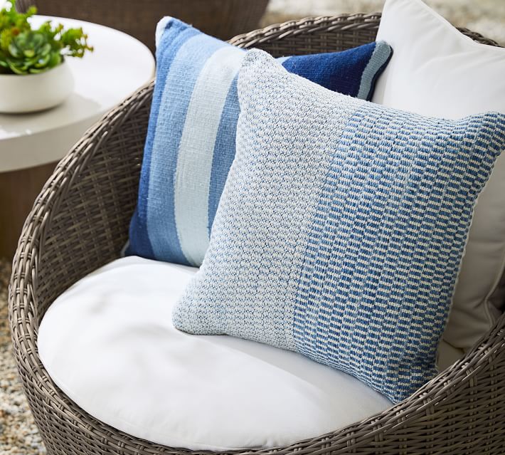 Blue and white striped and textured cushions on brown wicker outdoor sofa