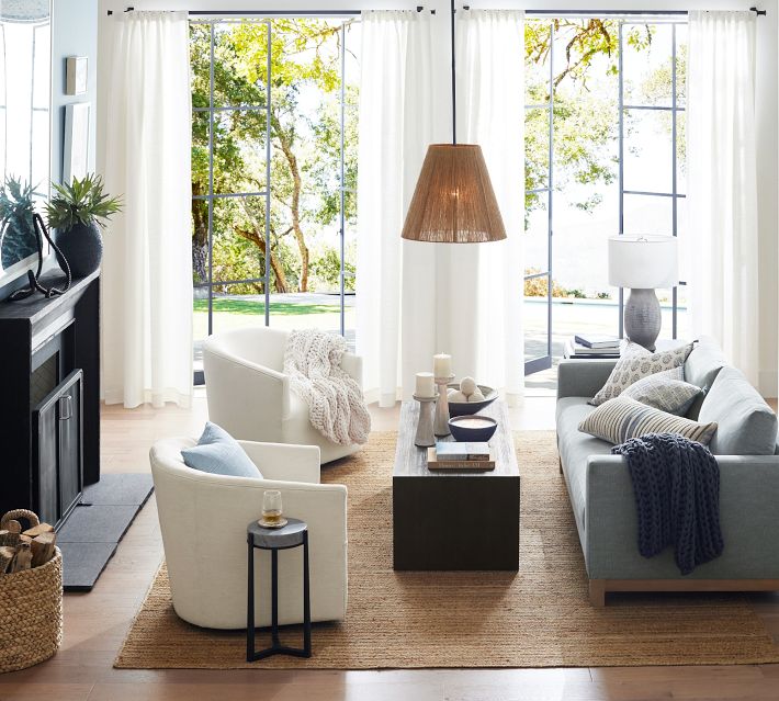Modern living room with white and beige seating, coffee table, and large windows