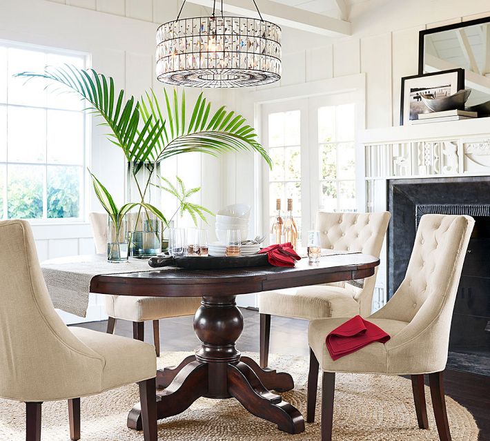 Elegant dining room with tufted beige chairs around a round table and a chandelier