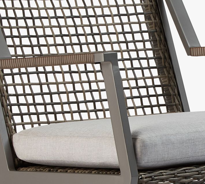 Close-up of the wicker back and arm of an outdoor rocking chair showing woven pattern and cushion
