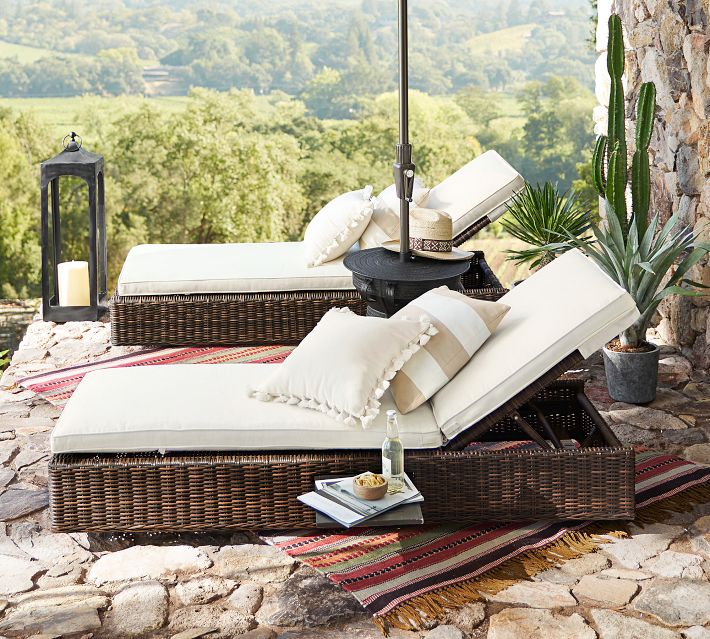 Outdoor loungers with beige cushions, umbrella, and table by scenic landscape