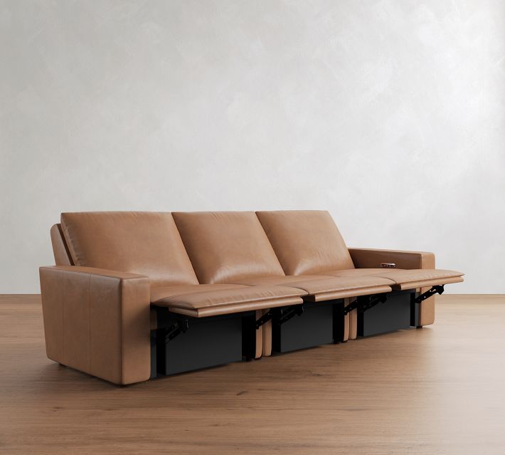 Side view of a tan leather sofa with leg structure and reclining mechanism visible under the seats.