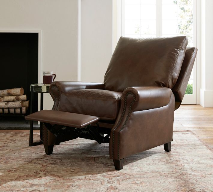 A brown leather recliner chair with its footrest pulled out in a living room, showing the ottoman extension and metal mechanism