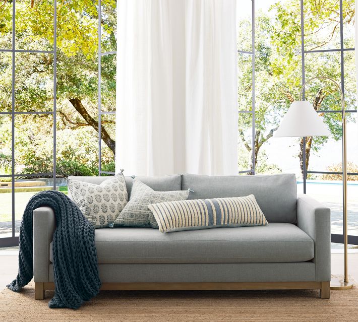 Bright living room with large windows, white sofa, blue-grey accents