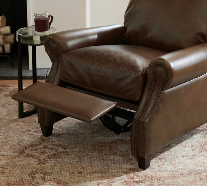 Close-up side view of the armrest and seat cushion of a brown leather recliner, showing nailhead trim and leather texture