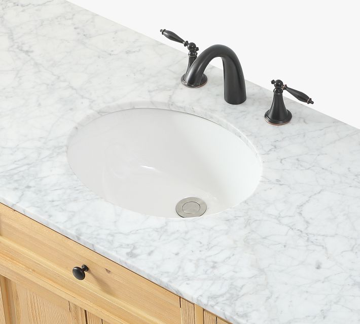 Close-up of marble sink countertop with undermount sink and black faucet.