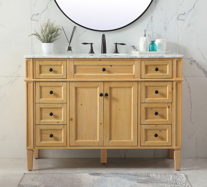 Wooden bathroom vanity with two rows of drawers and a pair of cabinet doors, in a marble-tiled bathroom.