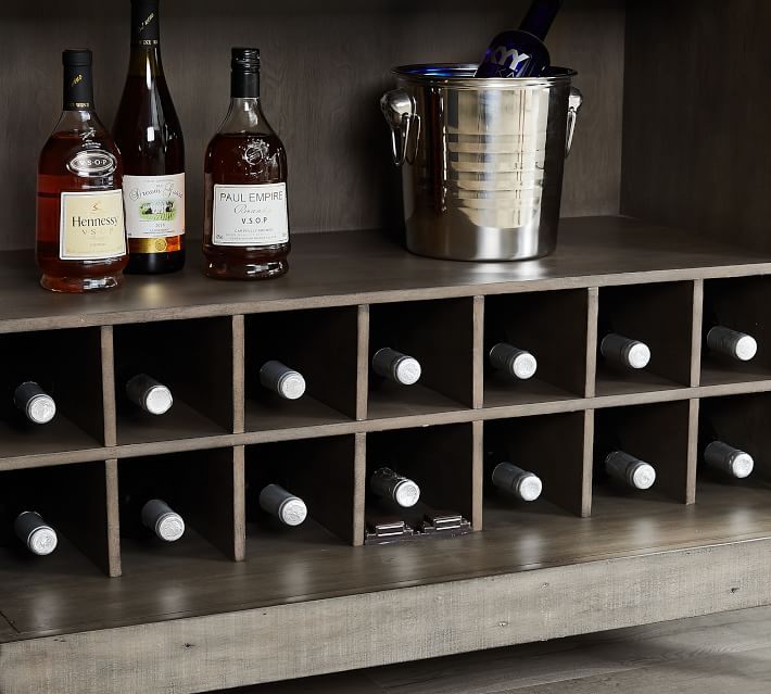 Shelf with bottles of liquor and a stainless steel bucket on a dark wood shelf.