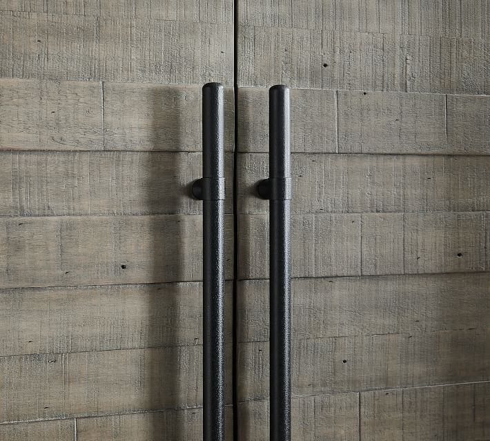 Close-up of two vertical black handles mounted on a wooden surface (cabinet door).