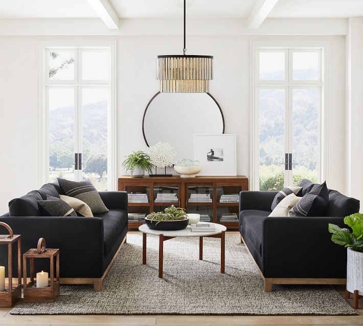 Modern living room with black sofas and round coffee tables, large window view