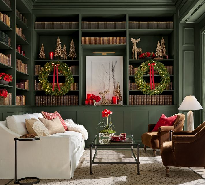 Living room scene with sofa, chairs, coffee table, Christmas decor, and built-in shelves.