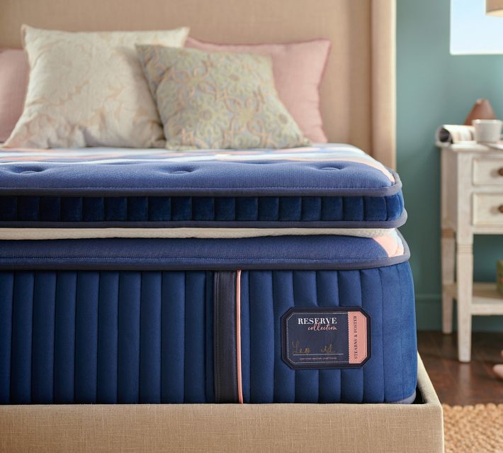 Close-up of the blue mattress with vertical quilting and a pink label on the side.