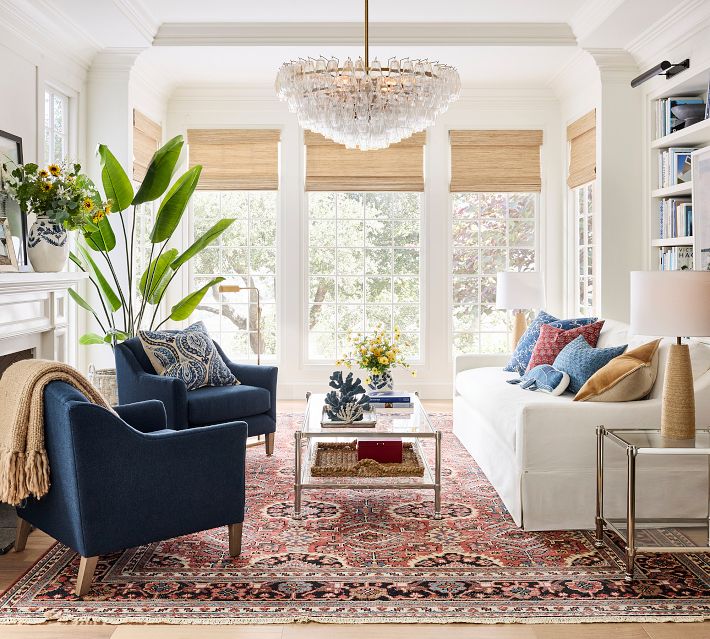 Living room with white sofa, lamps, and large windows, bright natural light.
