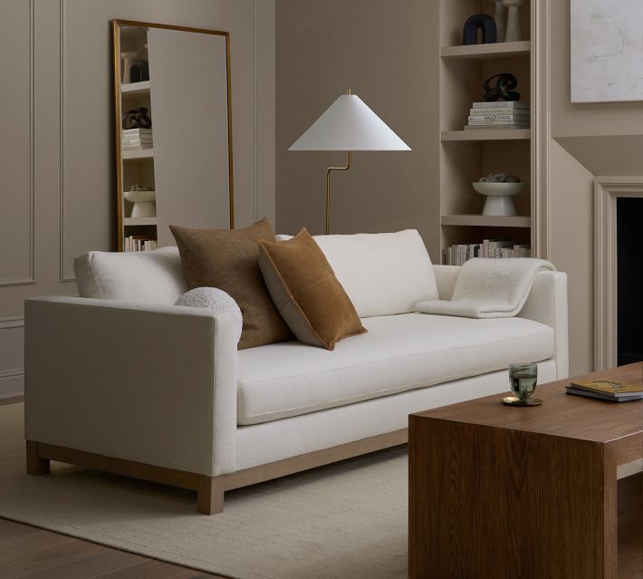 Living room with white sofa and brown coffee table and built-in shelves around fireplace