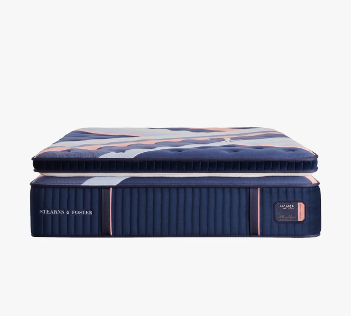 Side view of stacked blue mattress with navy cover and pink accent stripes, product label reads "Stearns & Foster".