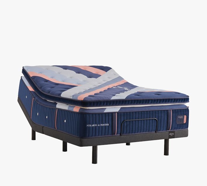 Side view of mattress with folded top pillow, showing legs of bed base.