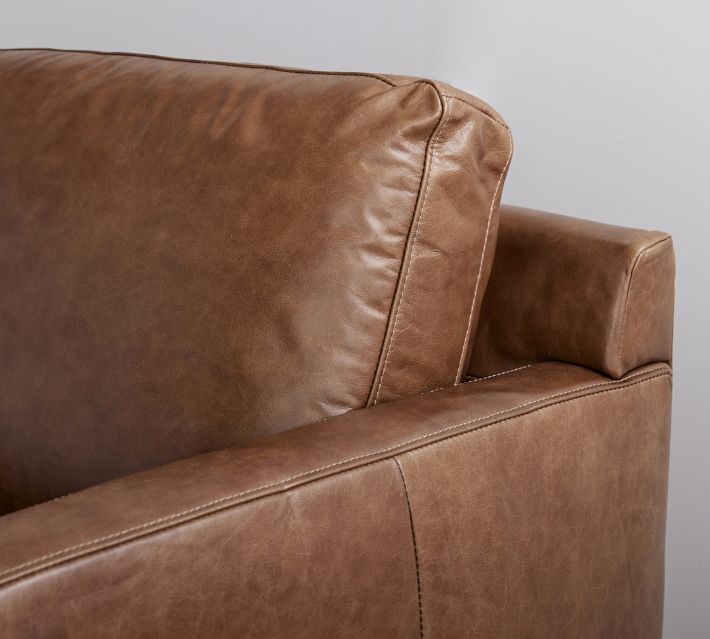 Top edge and side of brown leather sofa armrest