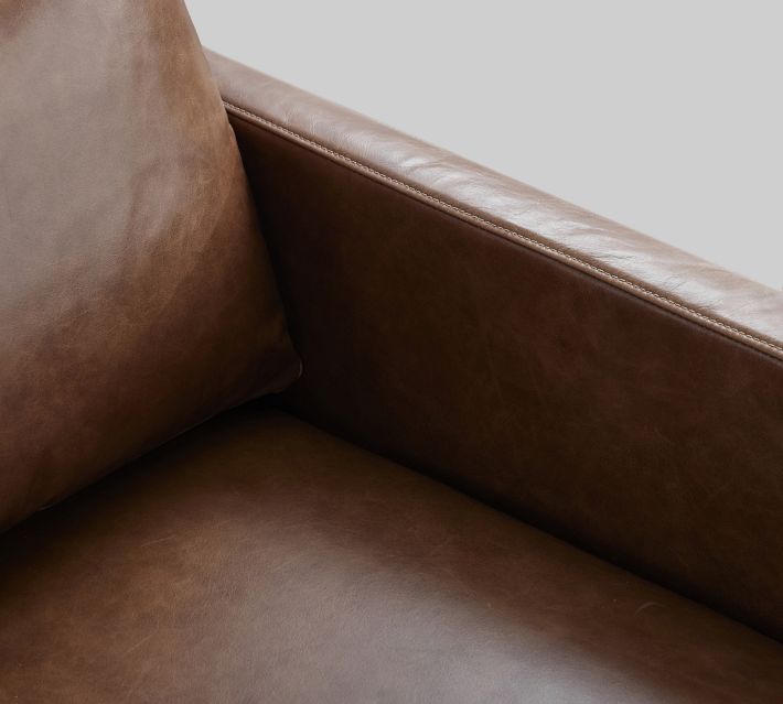 Close-up of brown leather armrest and seam on sofa