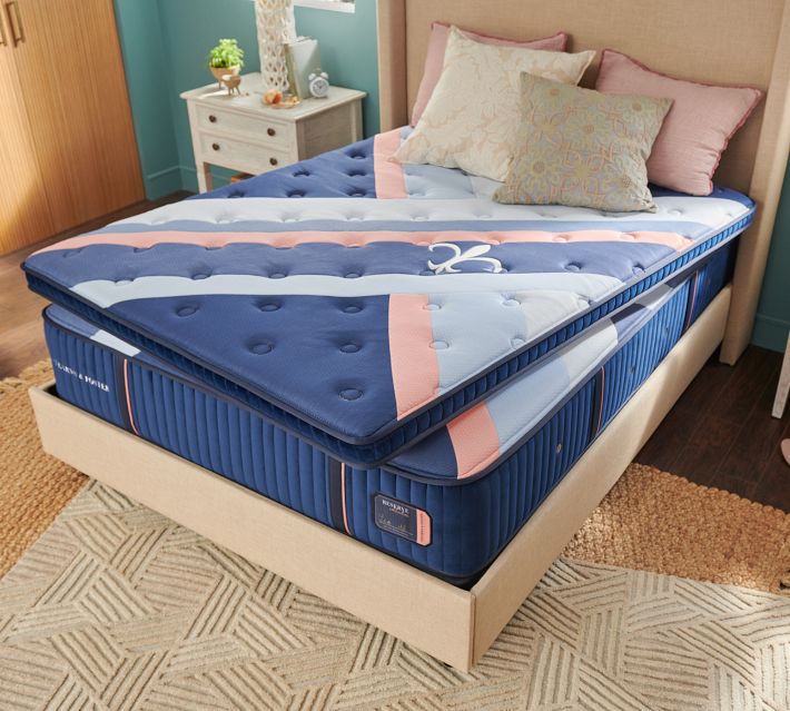 Top view of a folded blue mattress with matching pillows on a bed frame.