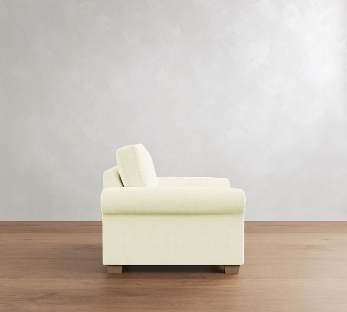 Light cream armchair shown in side profile, highlighting its depth and plush seat.
