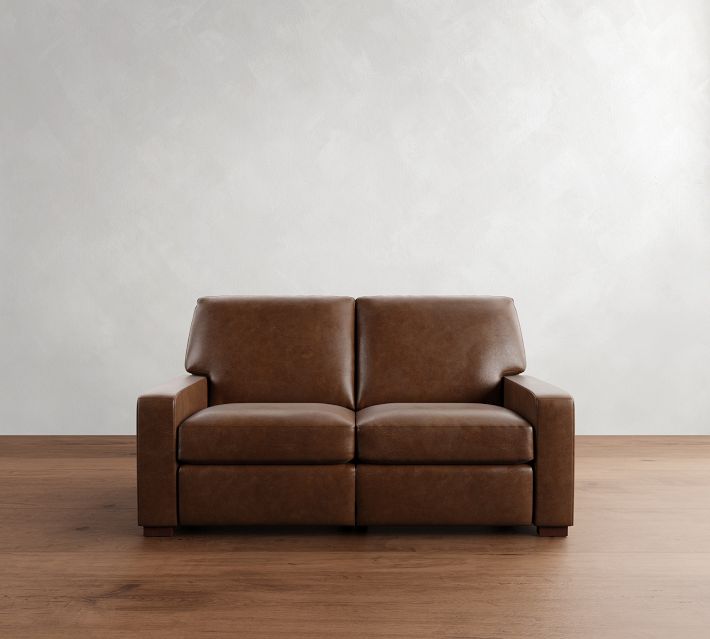 Three-seat brown leather sofa centered in room