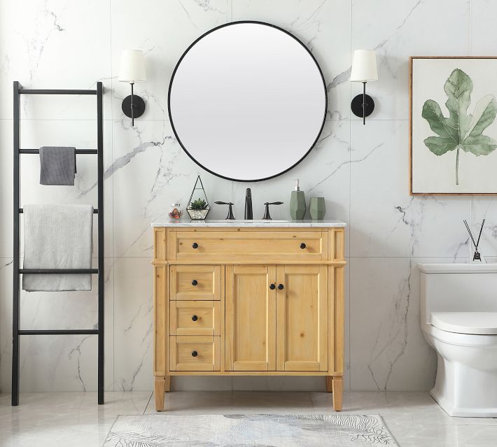 Bathroom with round mirror, wooden vanity, and towels on rack