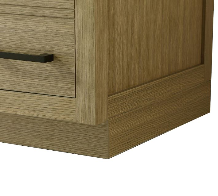 Corner of a wood vanity showing drawer and base, light wood finish.
