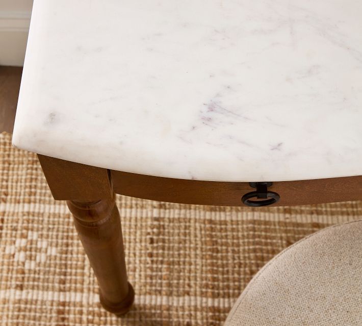 Close-up of a white marble tabletop with a corner lip and a small metal drawer pull beneath.