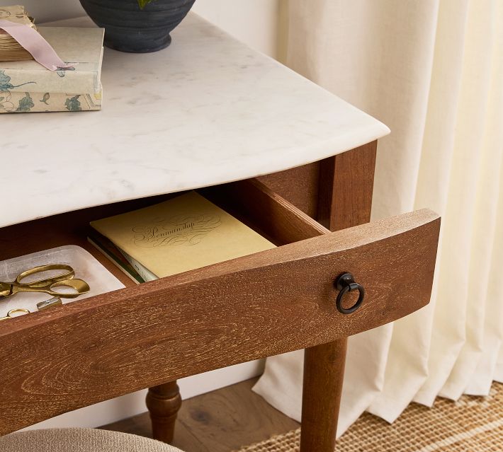 Open drawer showing contents including scissors and papers, marble-topped desk.