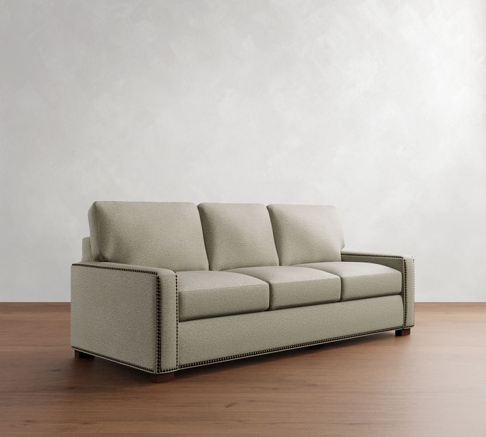 A taupe/grayish-beige three-seat sofa with three cushions and a longer seat.