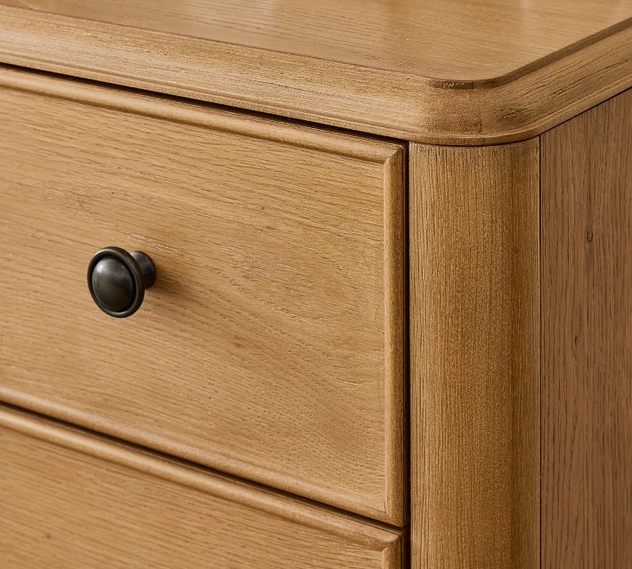 Close-up of a single wood drawer front with a round black knob from a wooden dresser.