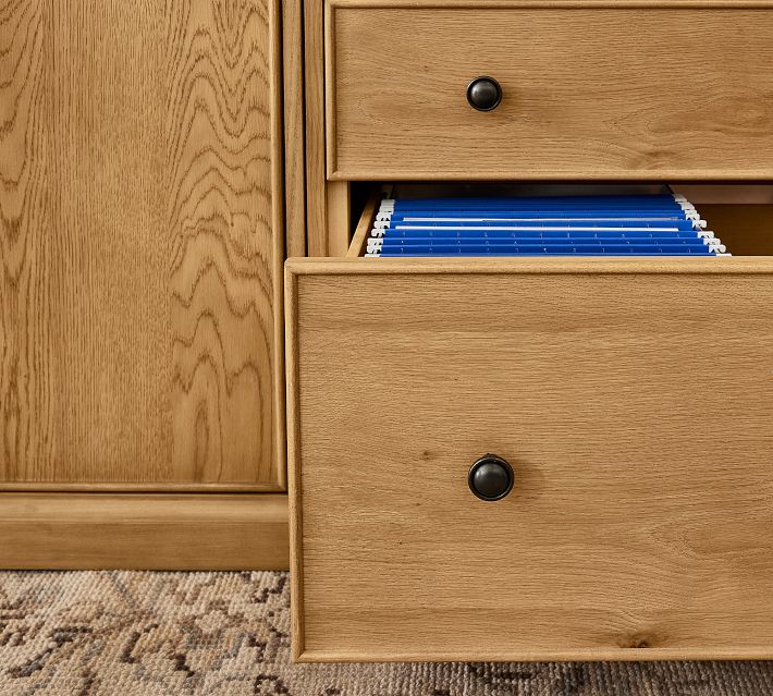 Open drawer from a wooden dresser showing interior with hanging file folders or notebooks.