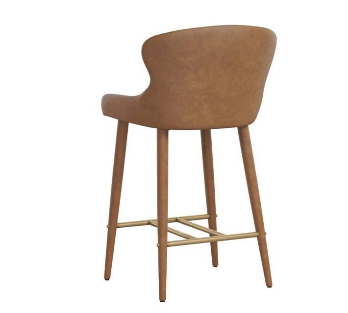 Rear-left view of a caramel brown upholstered bar chair showing back contour and wooden legs with footrest.