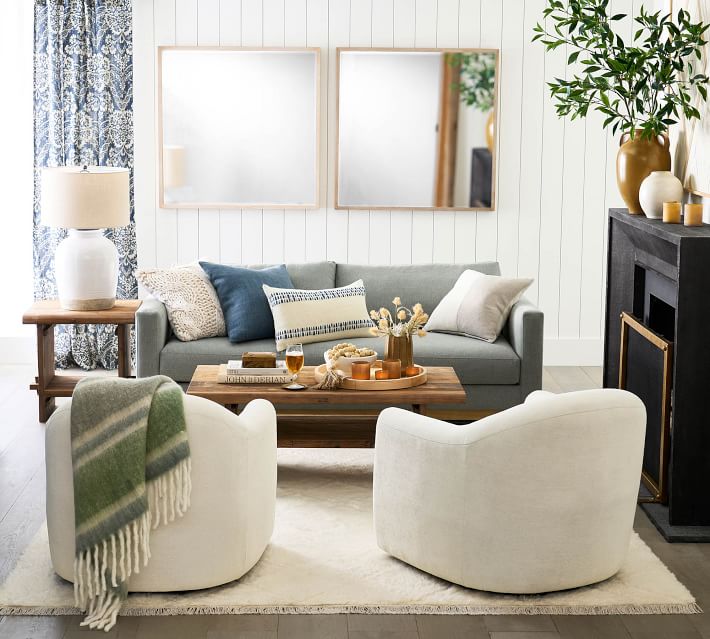 Living room with white sofa, blue/green accents, coffee table and large mirrors