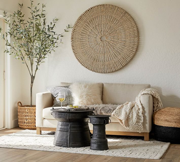Round woven wall art above seating area and olive tree