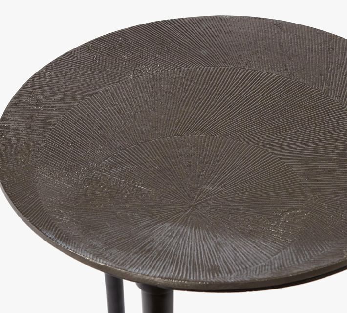 Close-up of the round textured surface of a dark metal table top with radial etched pattern