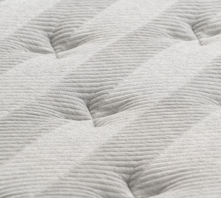 Close-up texture of a light gray quilted mattress surface with tufted pattern.